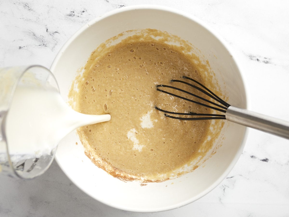 Milk pouring into the side of the bowl with the applesauce mixture. 