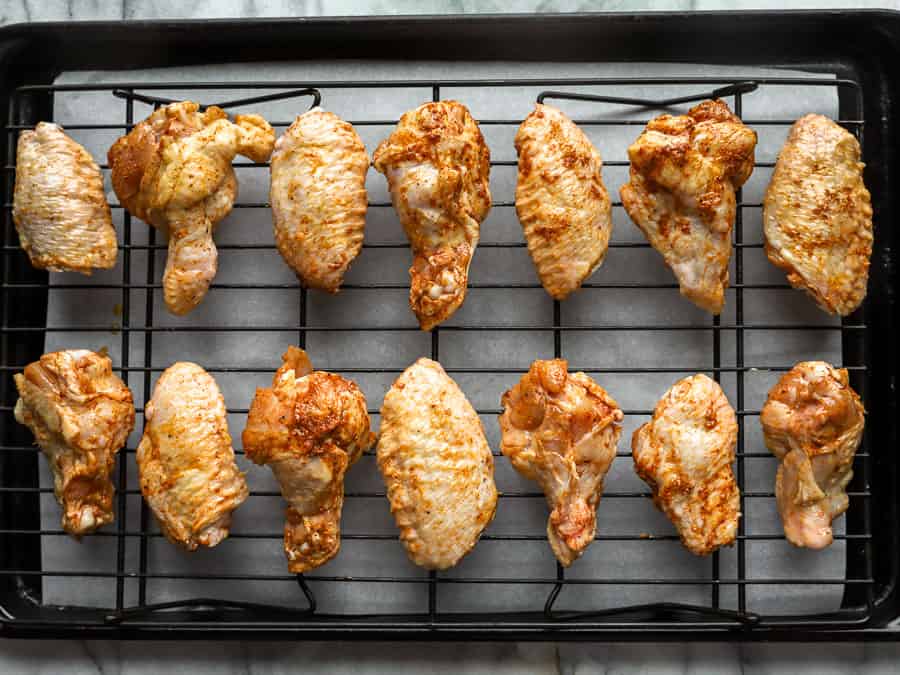 raw chicken wings on a wire rack set in a baking sheet.