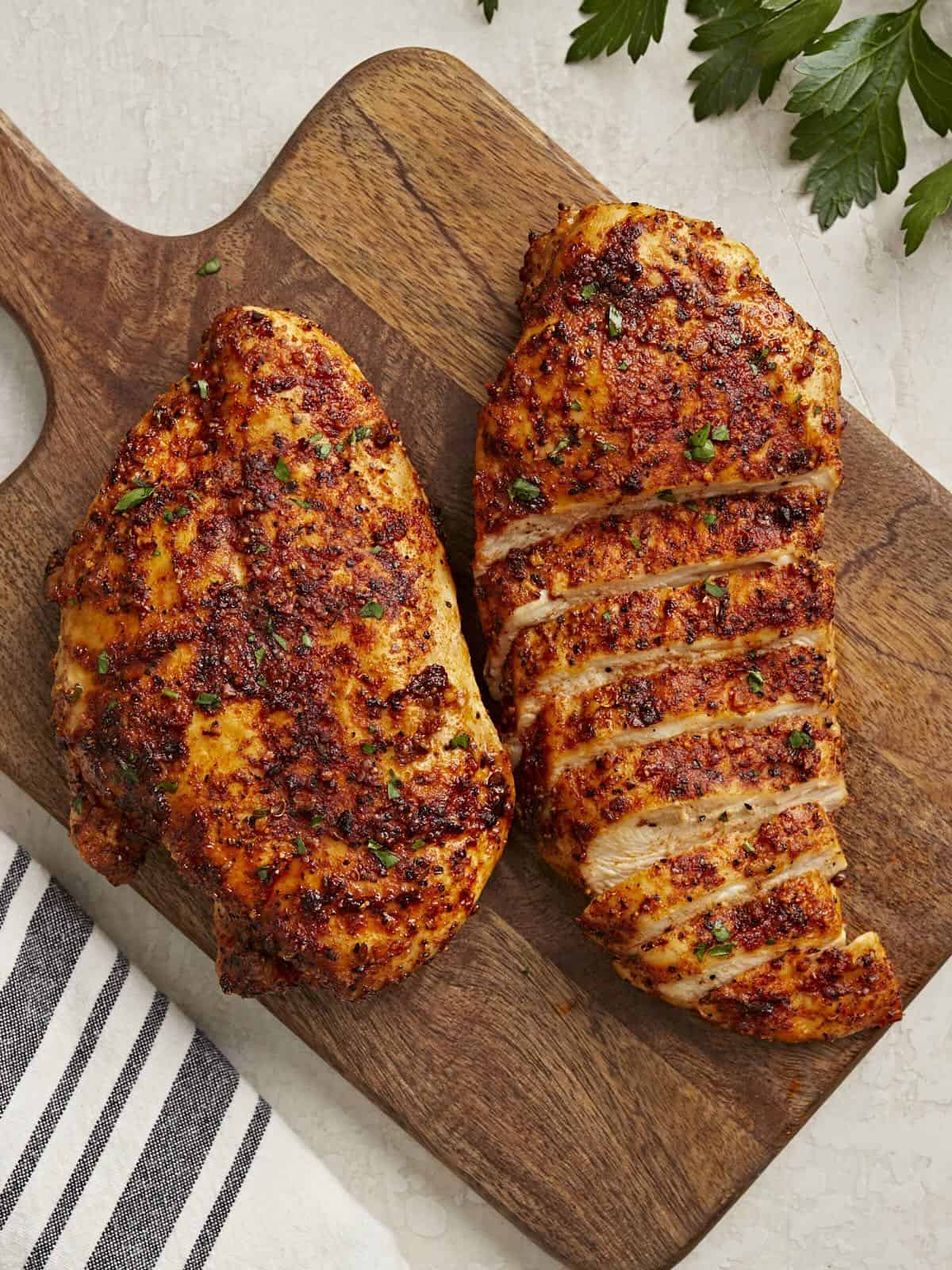 Sliced Air Fryer Chicken Breasts on a wood cutting board.