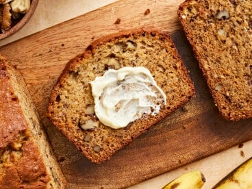 Overhead view of a slice of banana bread with butter spread on it.