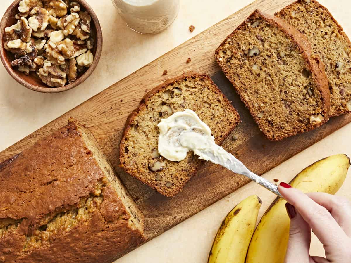 Butter being smeared onto a slice of banana bread.