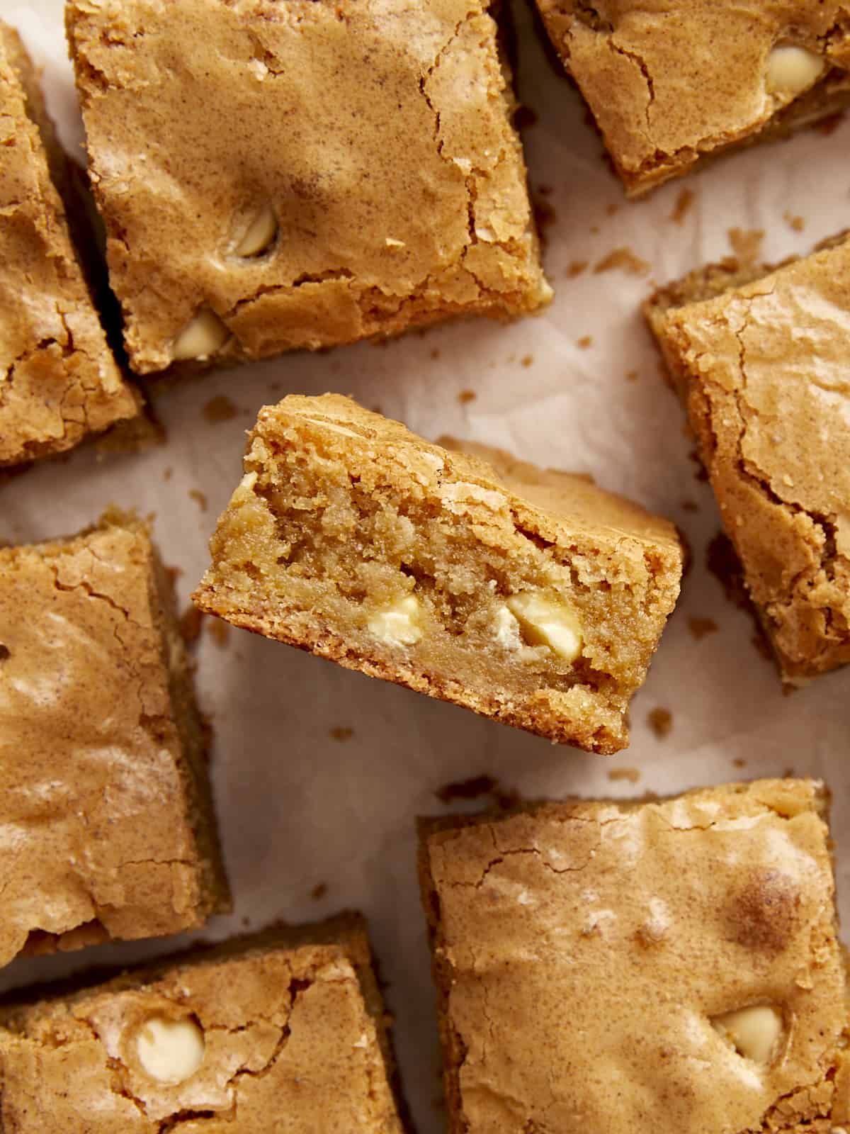 Close up overhead view of blondies on parchment paper with one blondie turned on it's side.