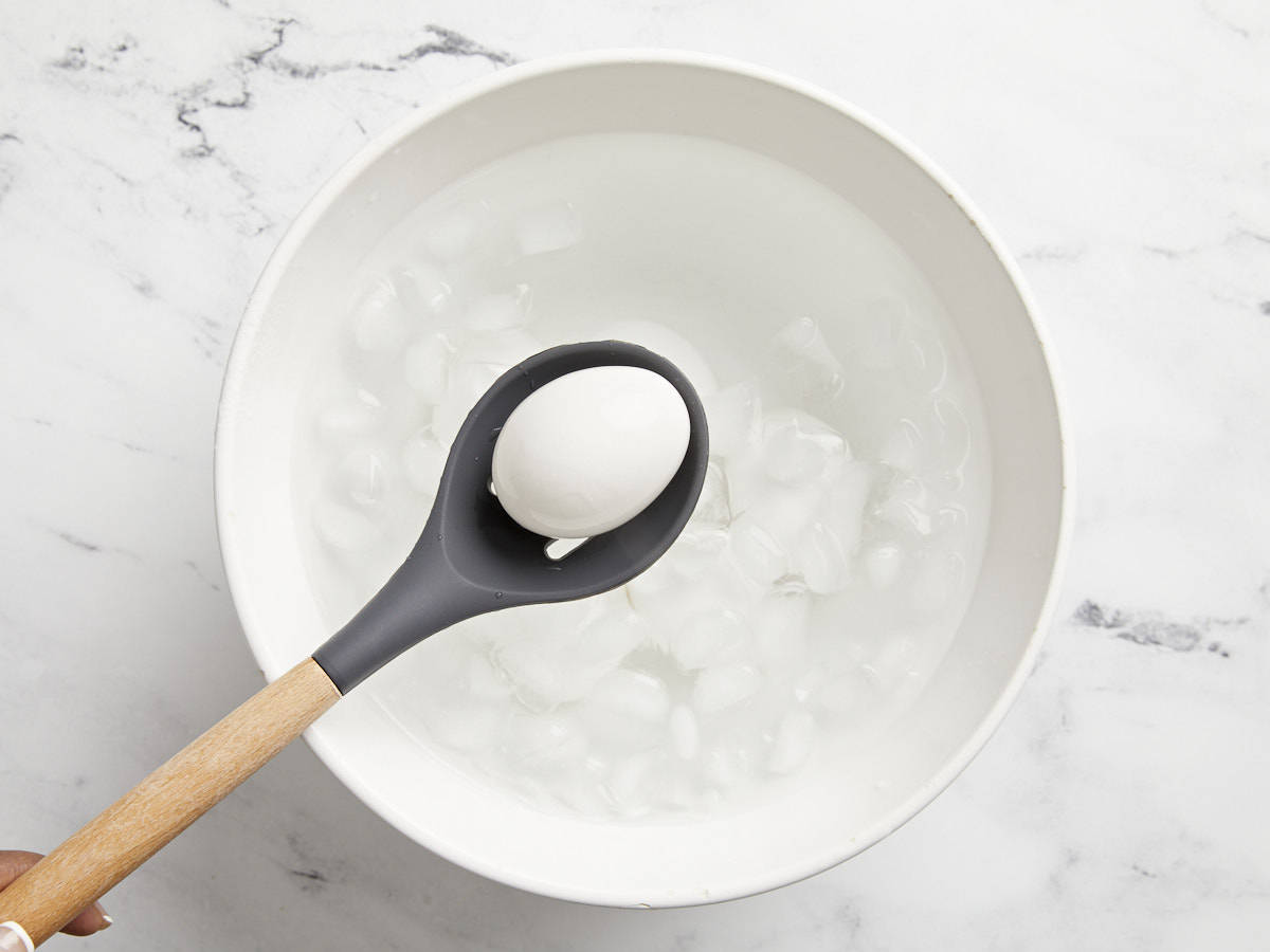 Hard boiled eggs being placed in an ice bath.