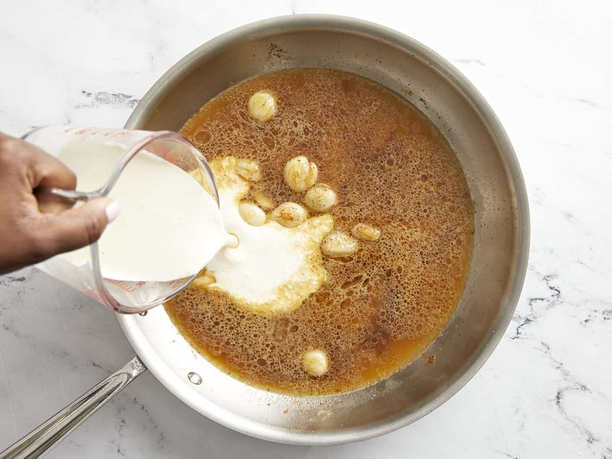 Chicken broth and heavy cream added to skillet.