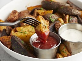 fork dipping an air fryer potato into ketchup.