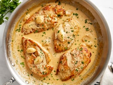 Overhead view of Creamy Garlic Chicken in a skillet with parsley garnished on top.