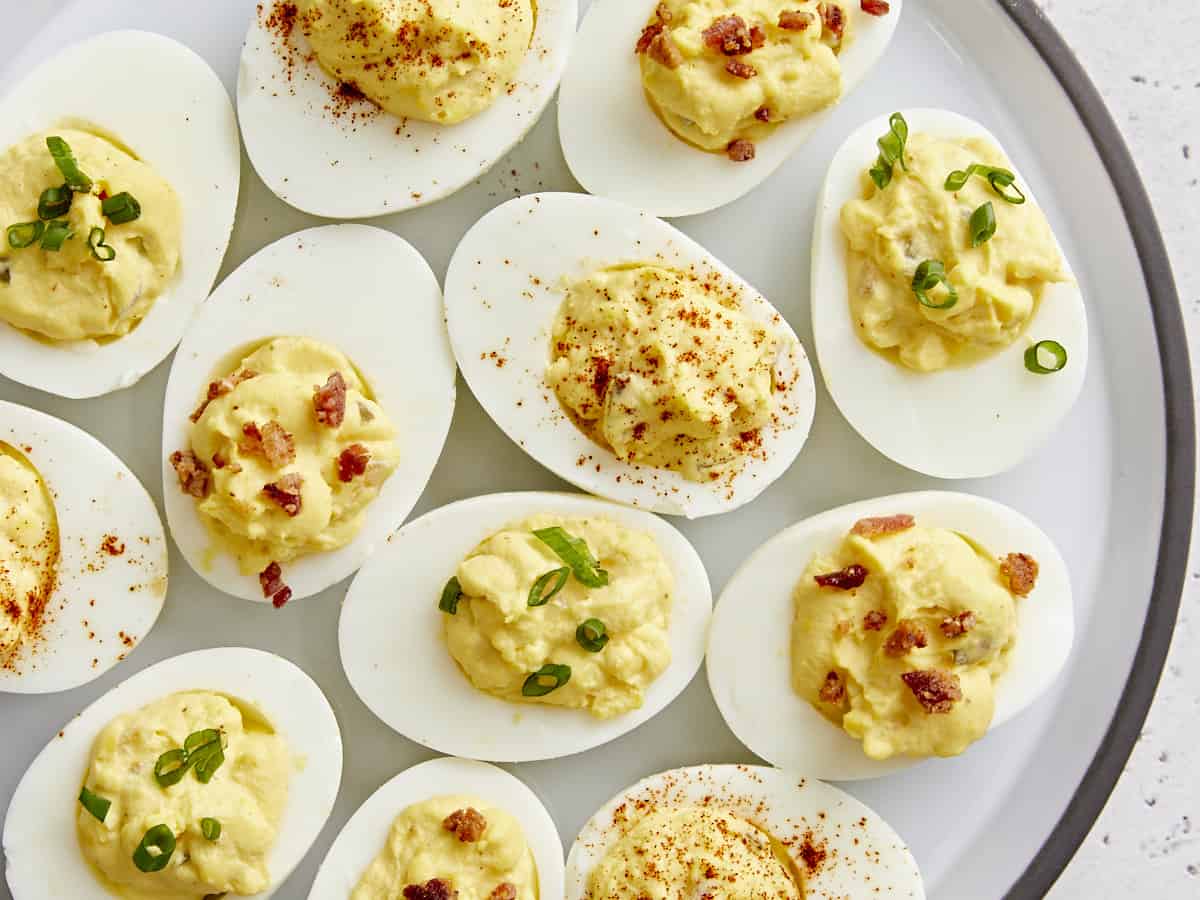 Overhead view of deviled eggs with different toppings on a serving platter.