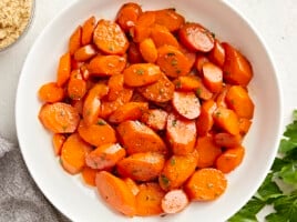 Overhead view of glazed carrots in a white serving dish.