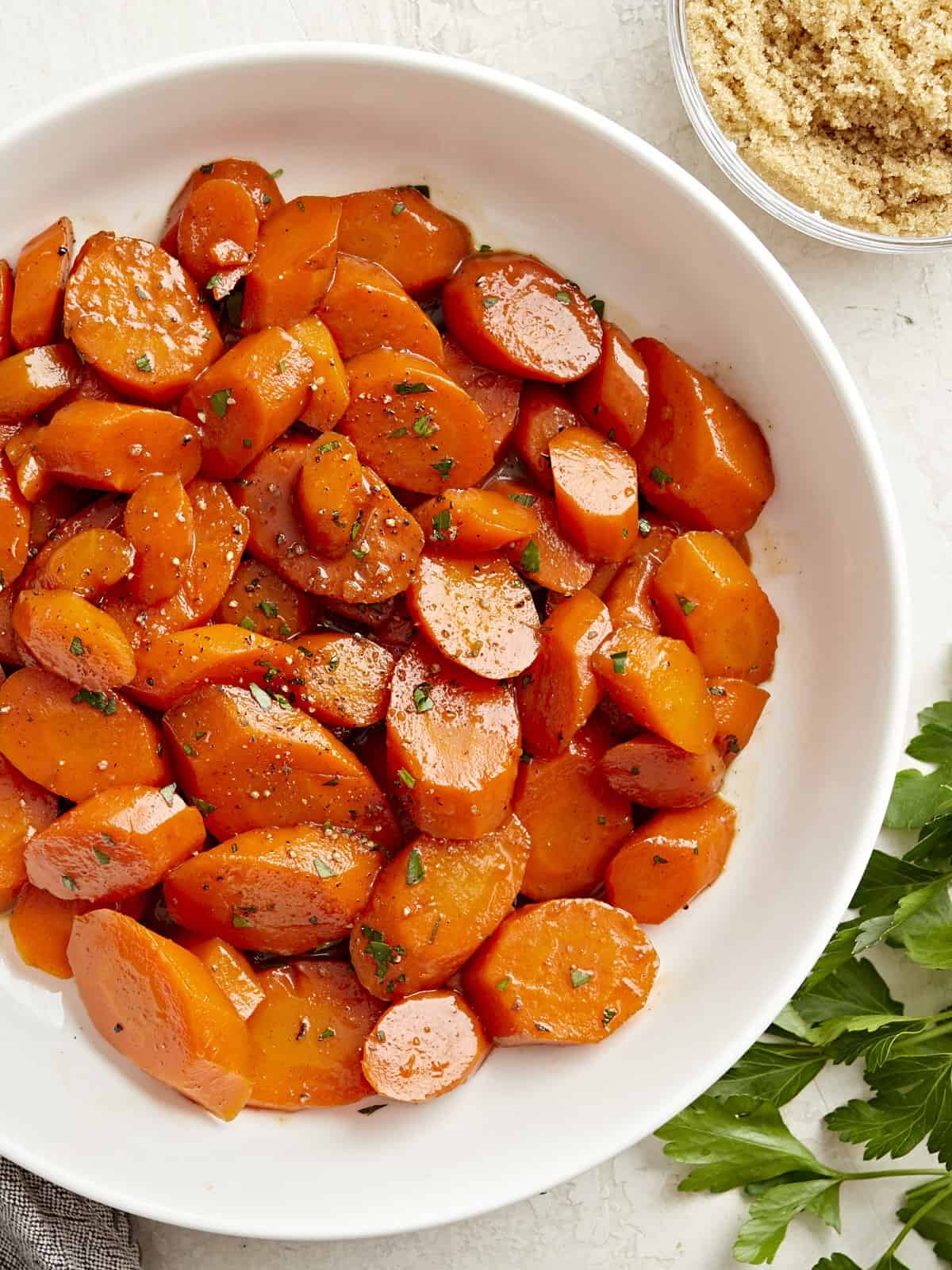 Overhead view of glazed carrots in a white serving dish.