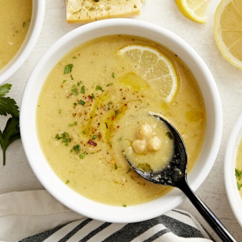 Overhead view of a bowl of lemony chickpea soup with a spoon in the middle.