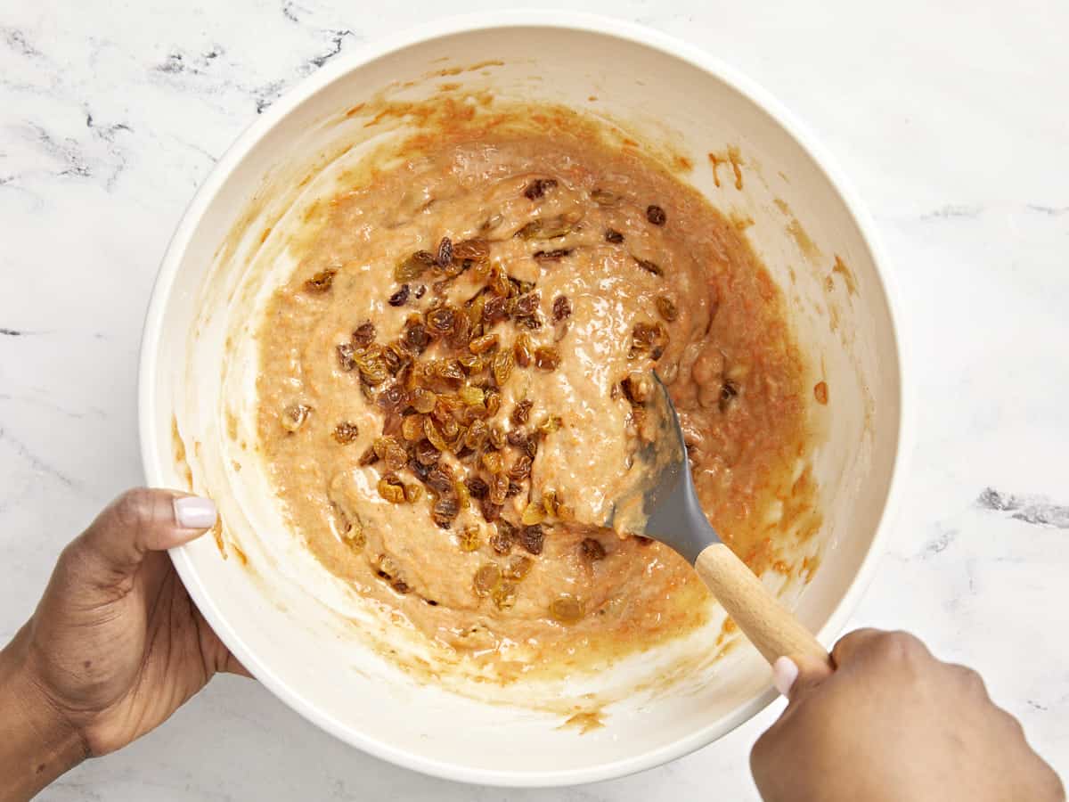 Golden raisins being added to carrot cake muffin batter.