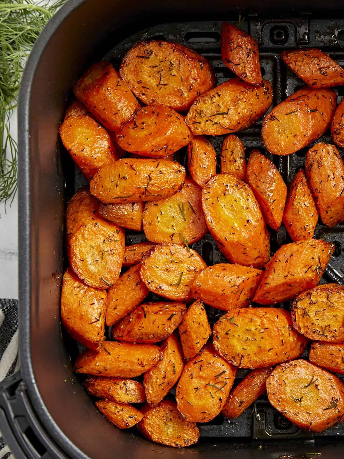 Overhead view of cooked carrots in a black air fryer basket.