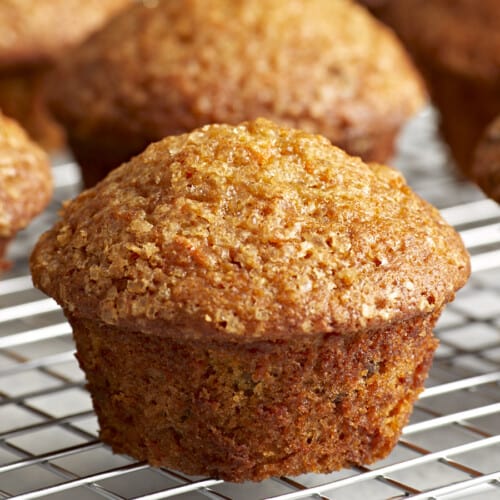 Close up side view of carrot cake muffins on a cooling rack.