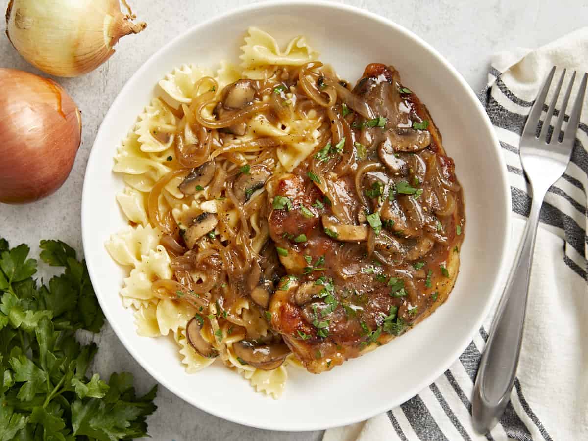 overhead view of chicken marsala in a white dish with bowtie pasta.