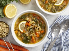 overhead view of 2 bowls of mediterranean lentil soup with lemon slices.