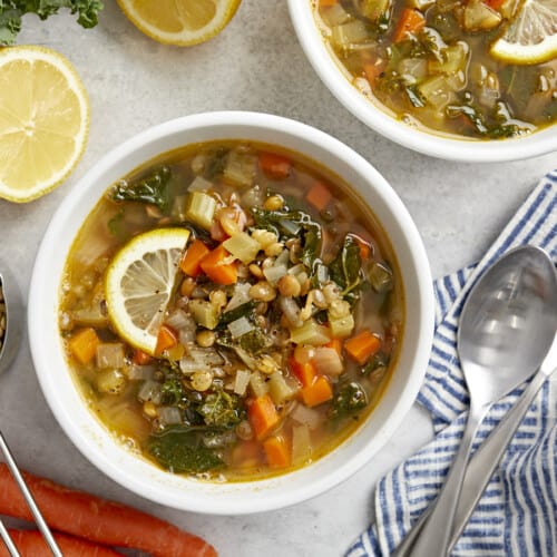 overhead view of 2 bowls of mediterranean lentil soup with lemon slices.