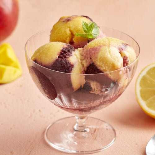 a serving of swirled yellow and purple sorbet in a glass coupe.