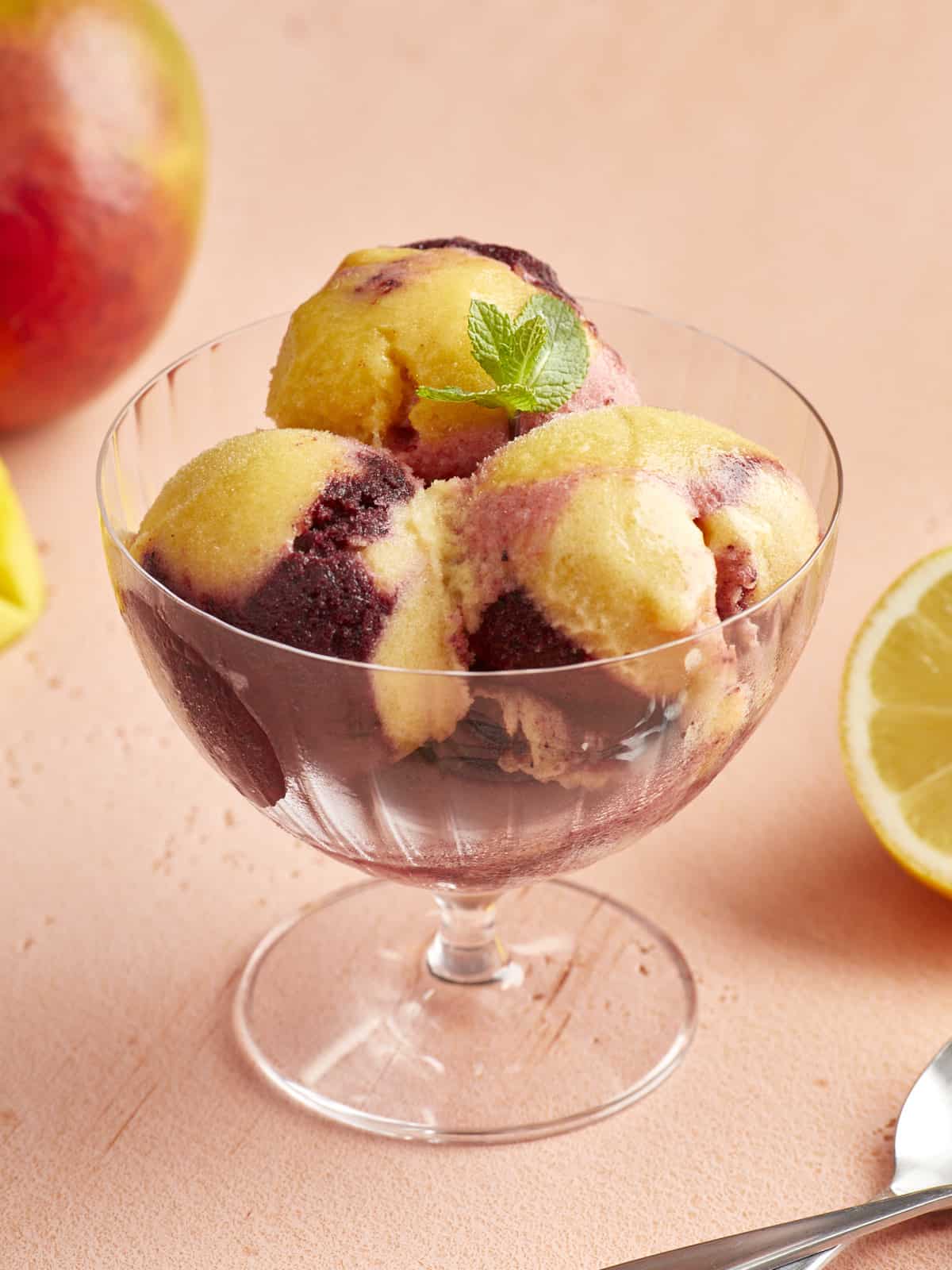 a serving of swirled yellow and purple sorbet in a glass coupe.