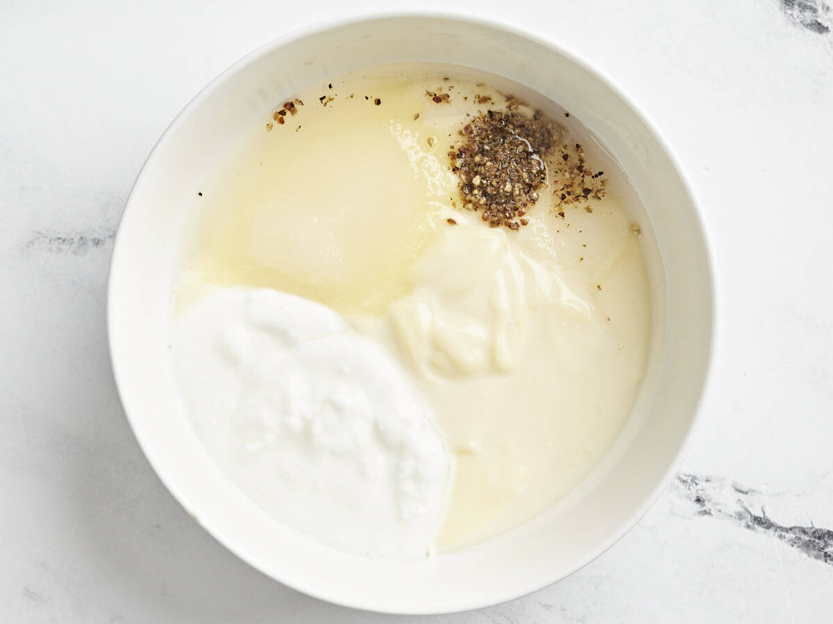 ingredients for salad dressing in a white bowl.