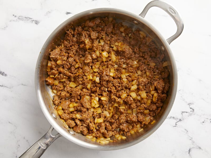 Cooked chorizo and onion in a skillet. 