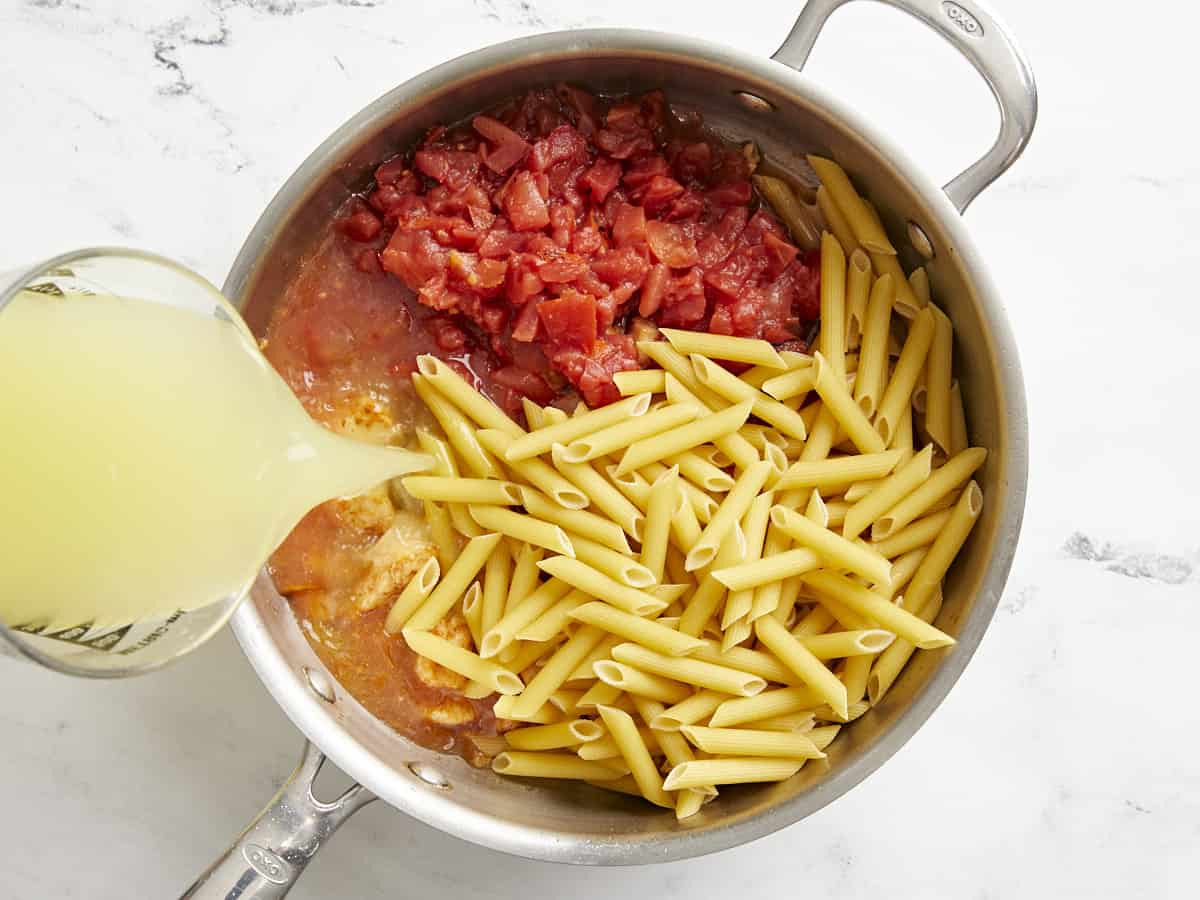 Tomatoes, pasta, and broth added to the skillet.