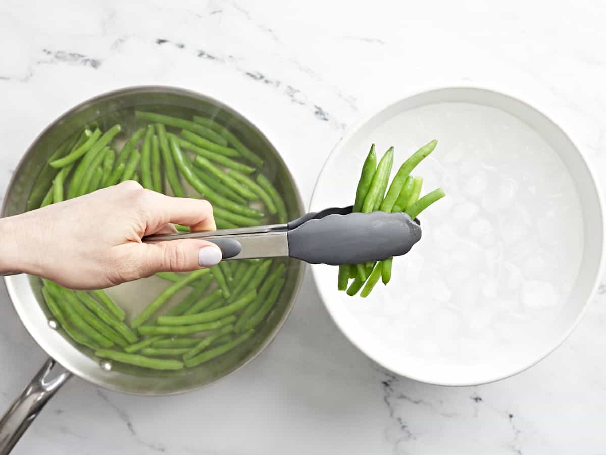 blanched green beans being transferred to ice water.