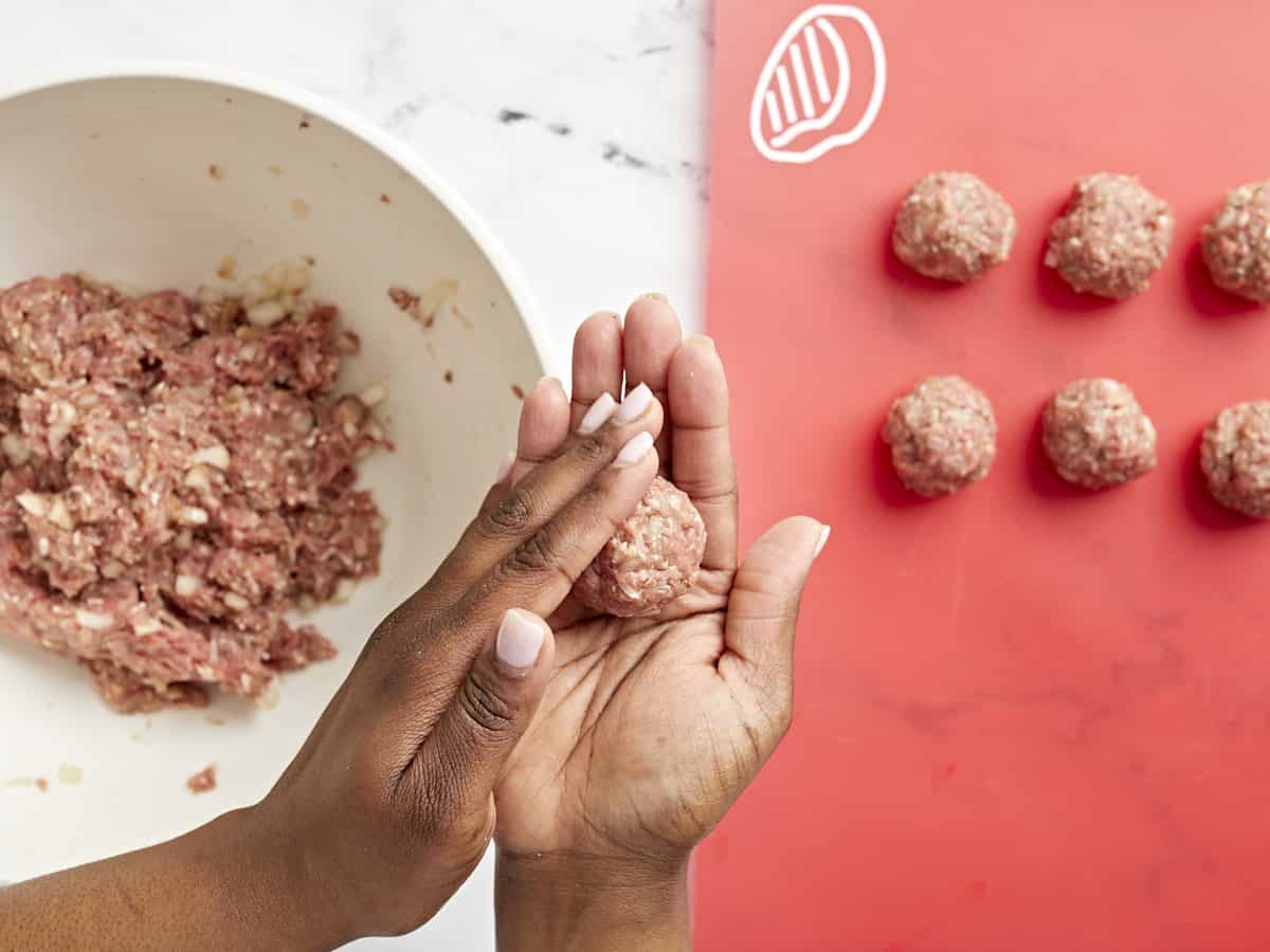 Overhead view of meatballs being rolled and shaped.