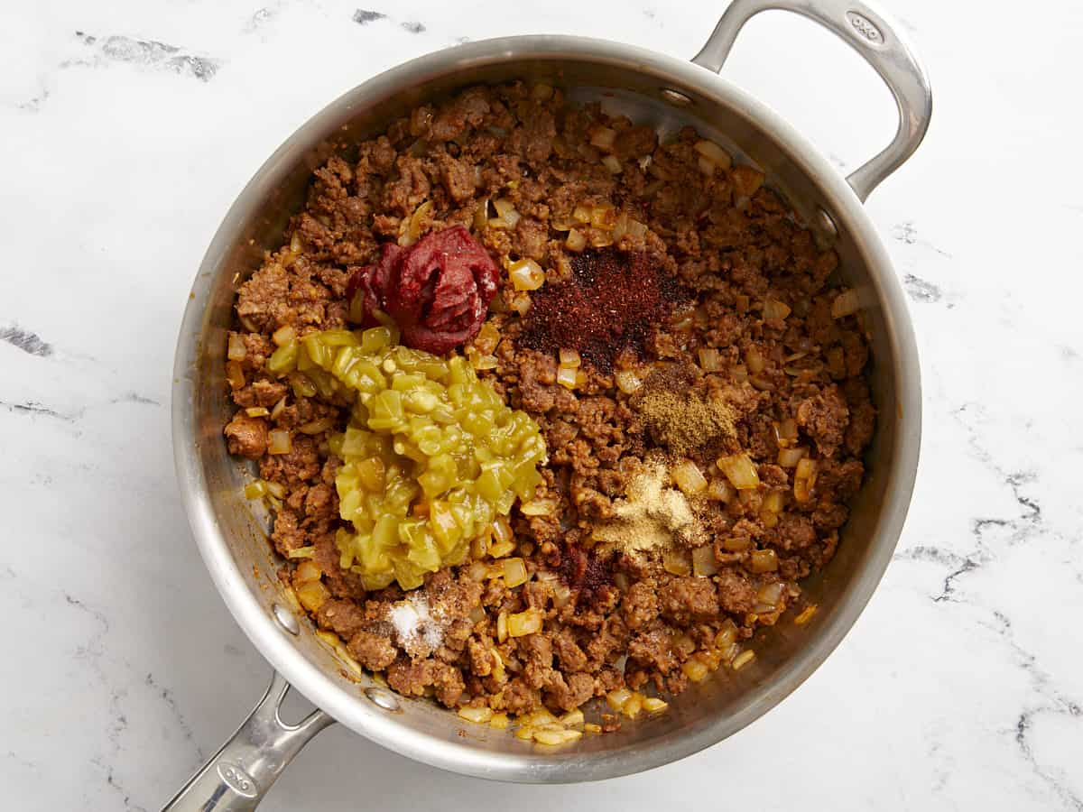 Green chiles, tomato paste, and spices added to the skillet. 