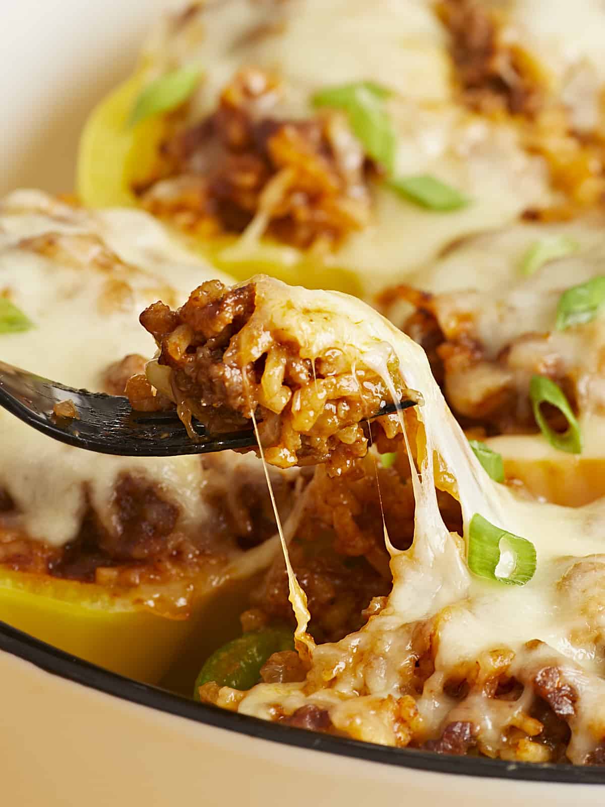 Close up side view of a fork lifting some of the filling out of a stuffed bell pepper.