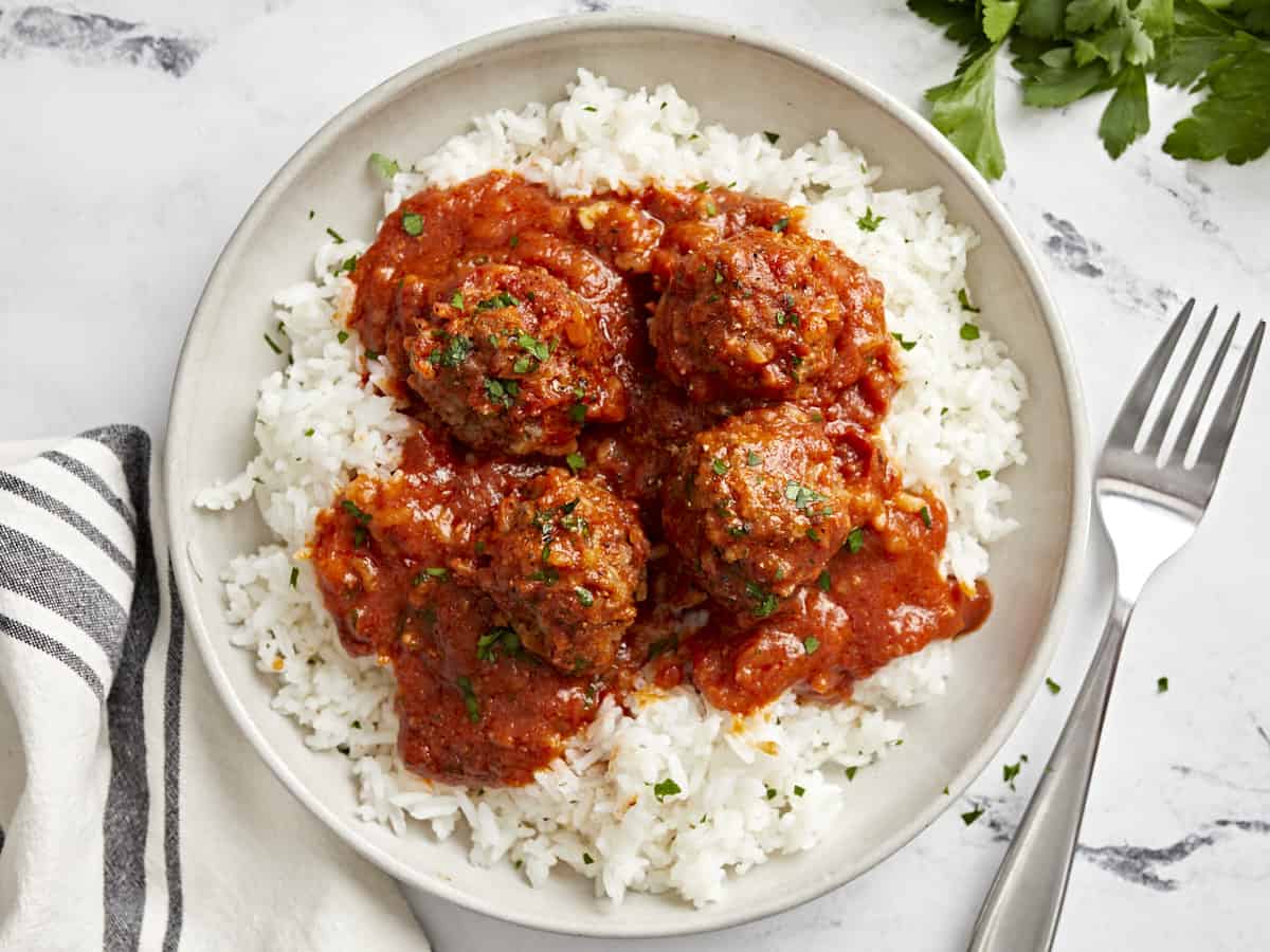 Overhead view of porcupine meatballs on a serving plate with white rice.