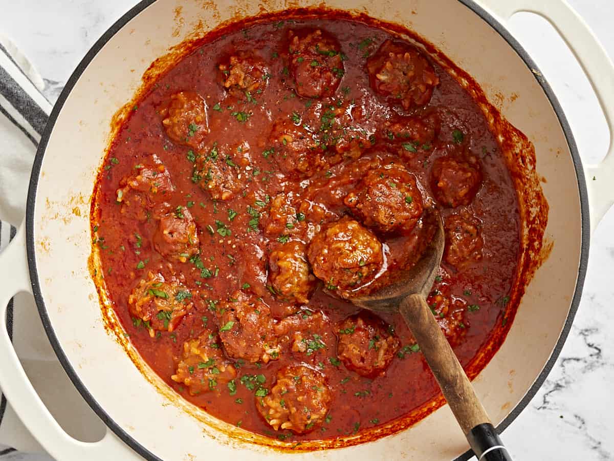 Overhead view of porcupine meatballs in a dutch oven covered in tomato sauce.