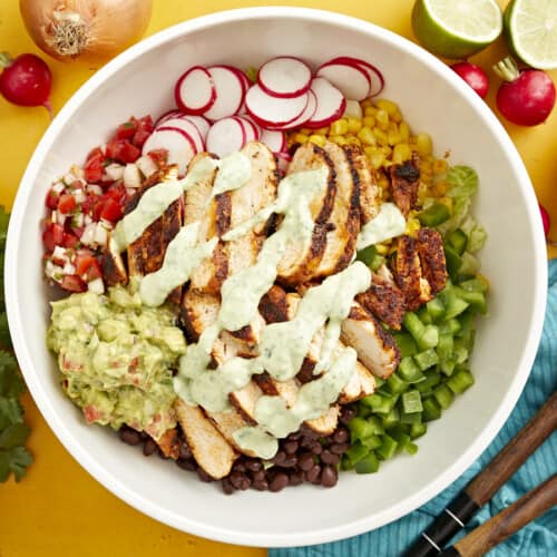 creamy avocado dressing drizzled over santa fe salad in a large white bowl.