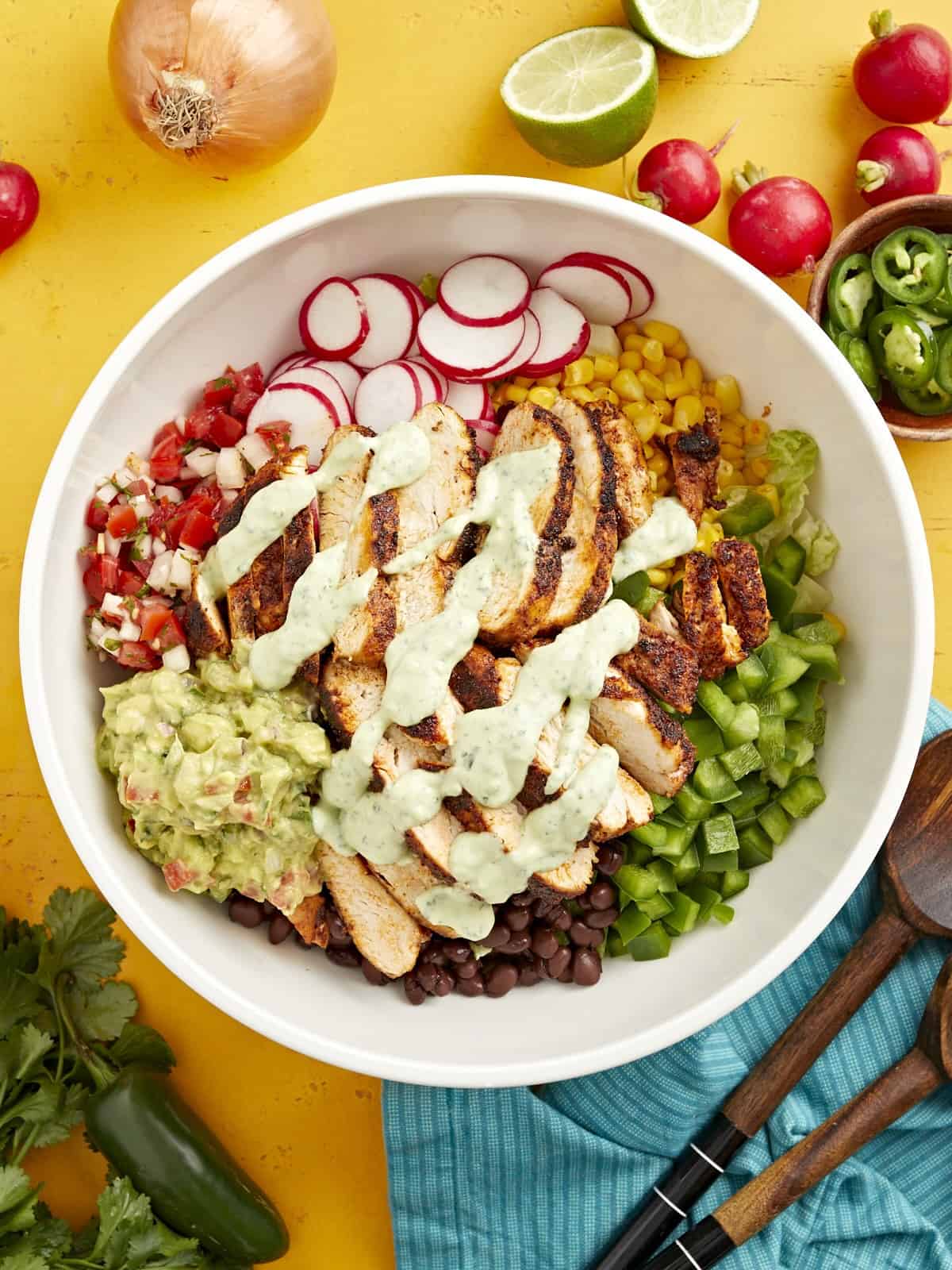 creamy avocado dressing drizzled over santa fe salad in a large white bowl.