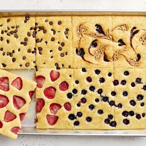 Overhead view of sheet pan pancakes cut into squares with one slice being lifted out.