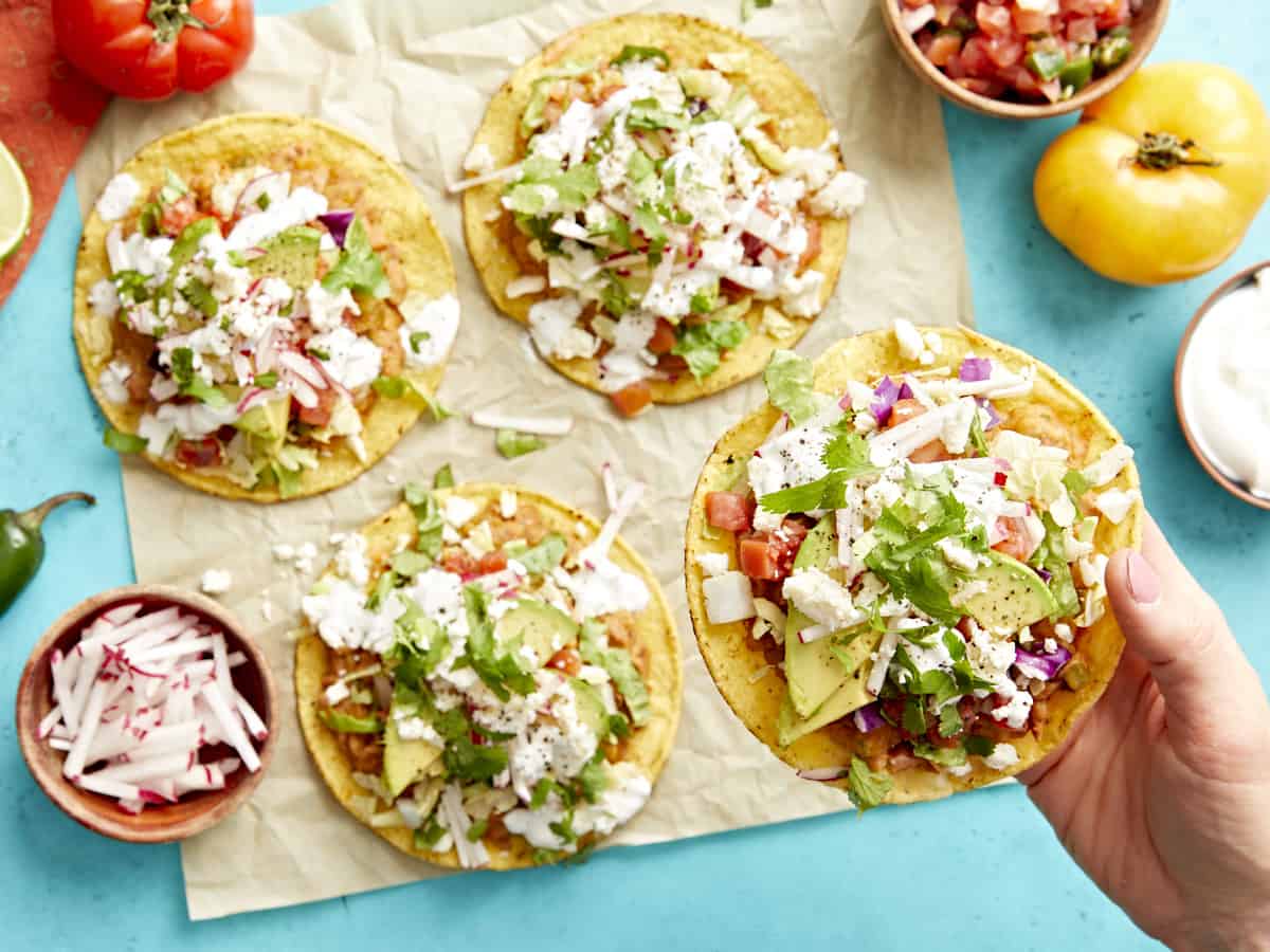 holding a tostada over a table topped with tostadas.