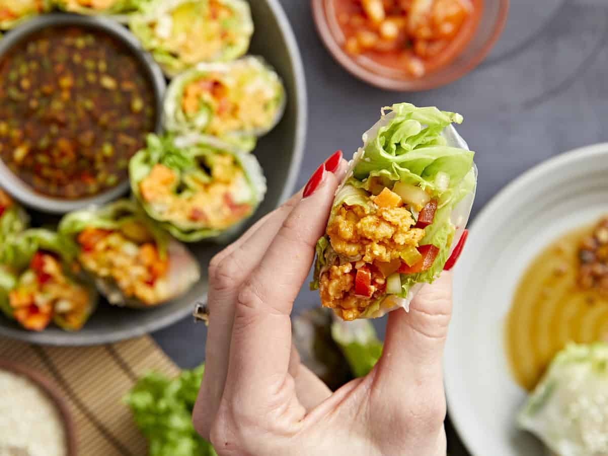 holding a kimchi spring roll to show the filling.