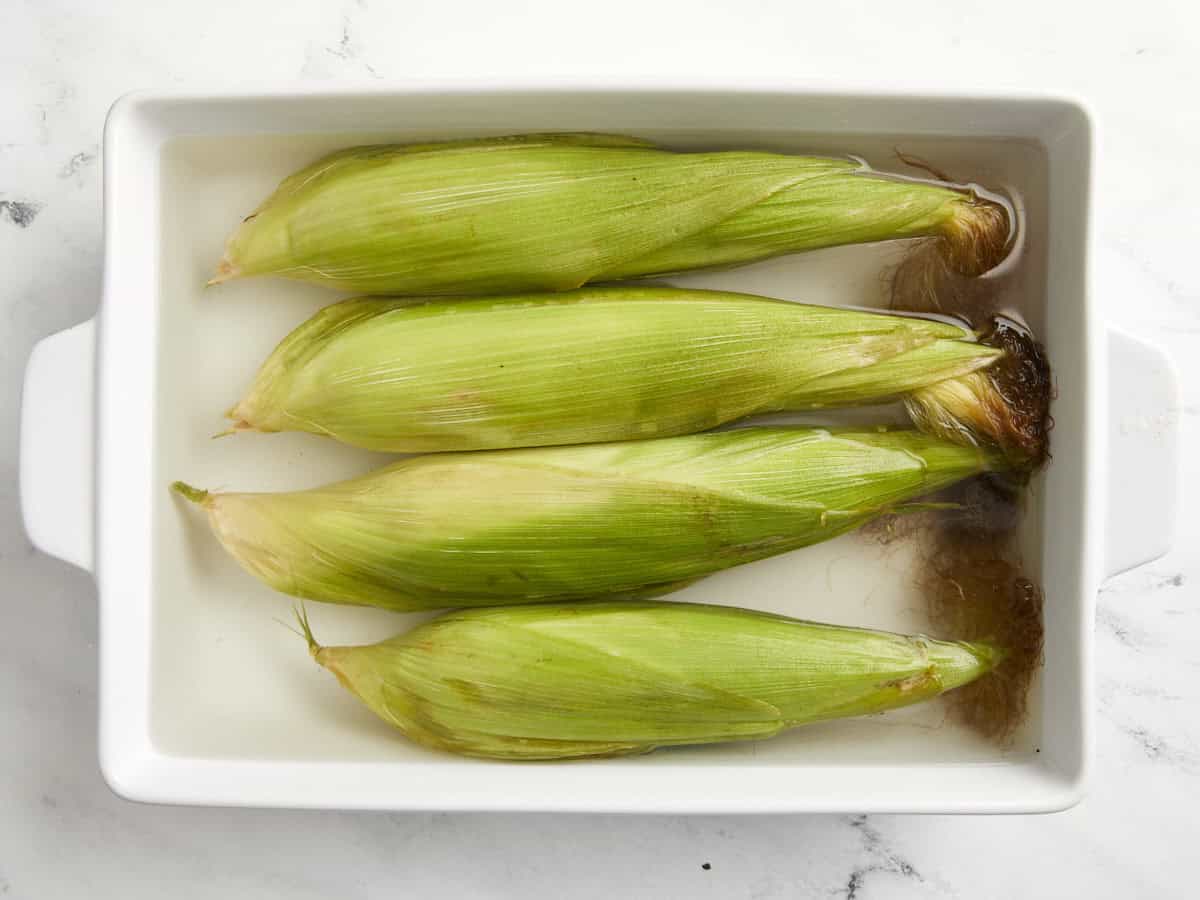 4 ears of corn soaked in water.