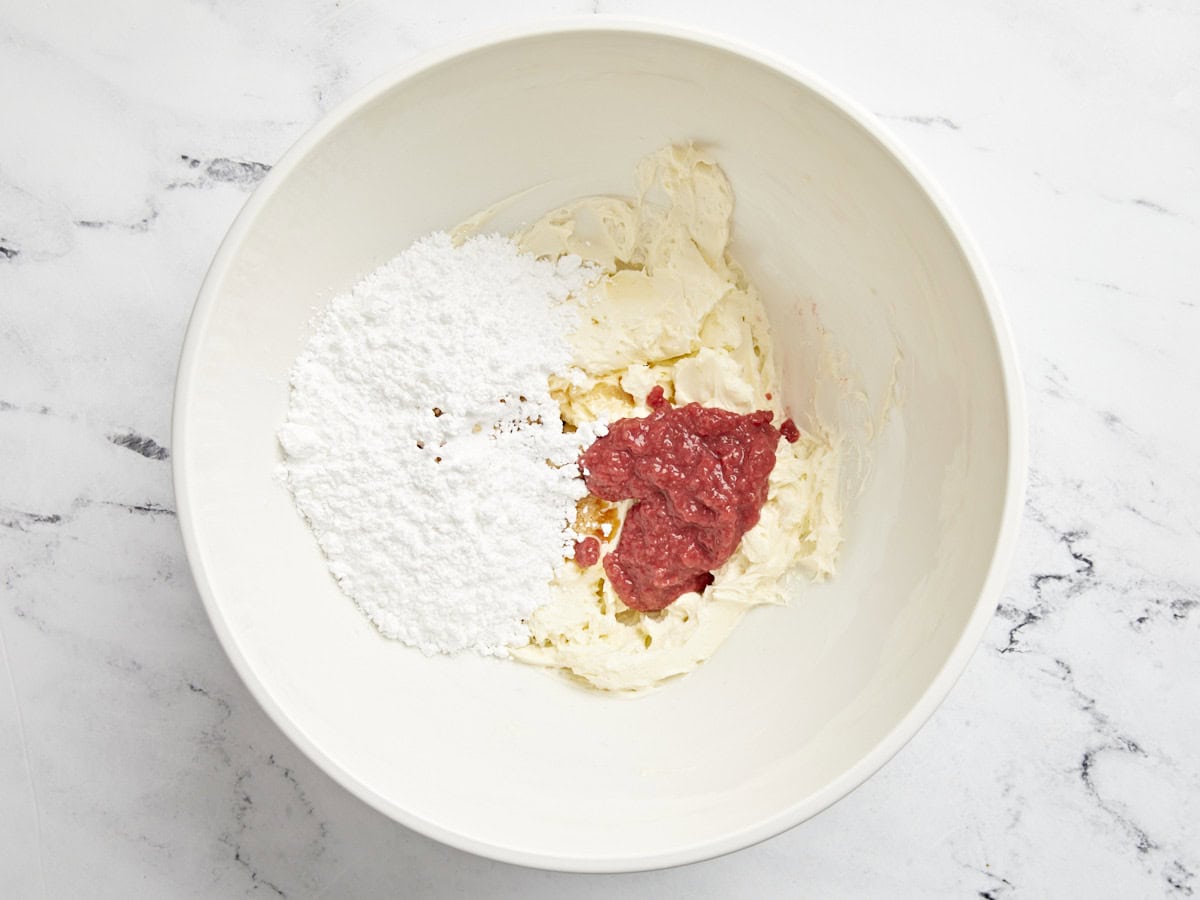 Strawberry cream cheese frosting ingredients added to a bowl.