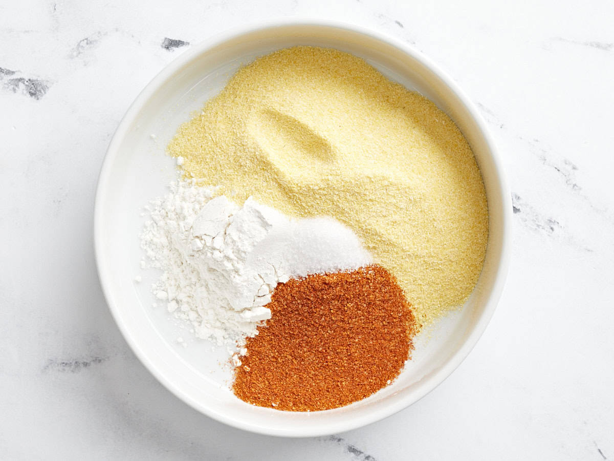 flour, cornmeal, and bbq seasoning in a white bowl.