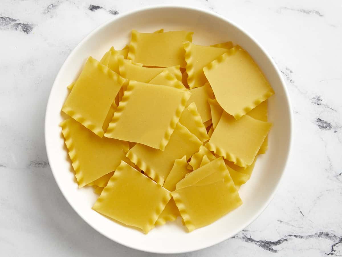 Broken lasagna noodles in a white bowl.