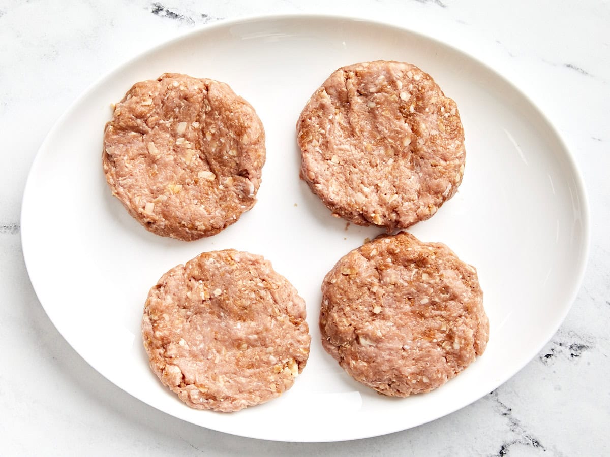 4 turkey burger patties on a white plate.