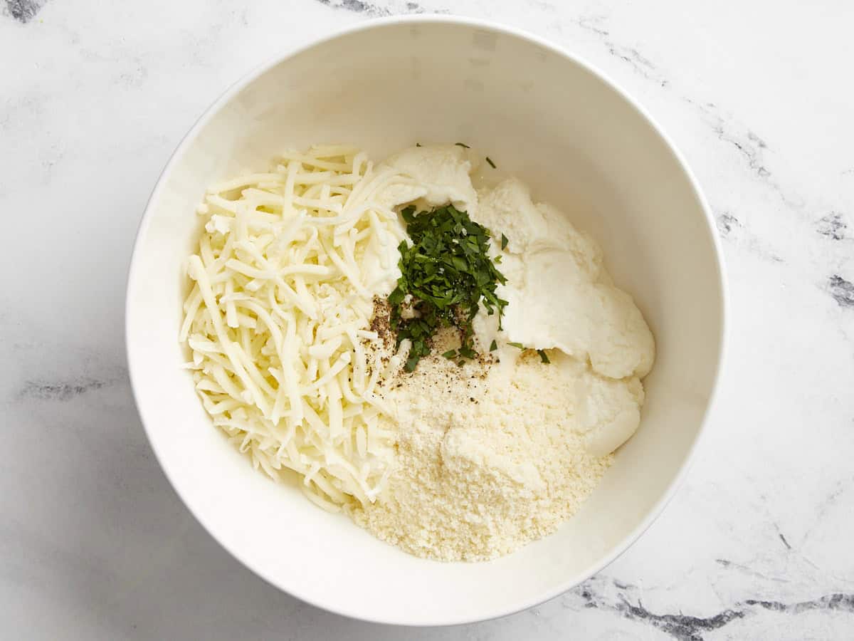 Ricotta, mozzarella and parmesan cheese added to a small bowl.