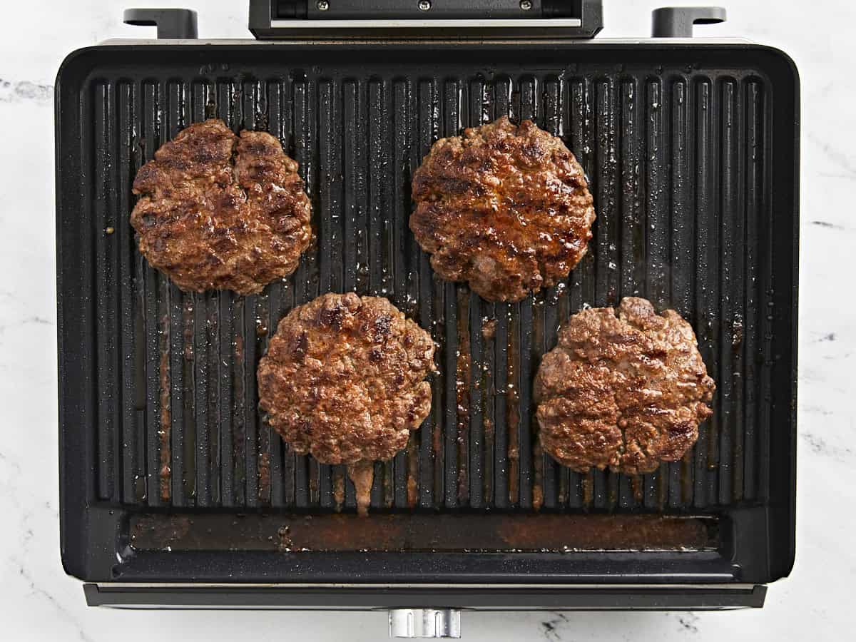 Hamburgers flipped on a grill.