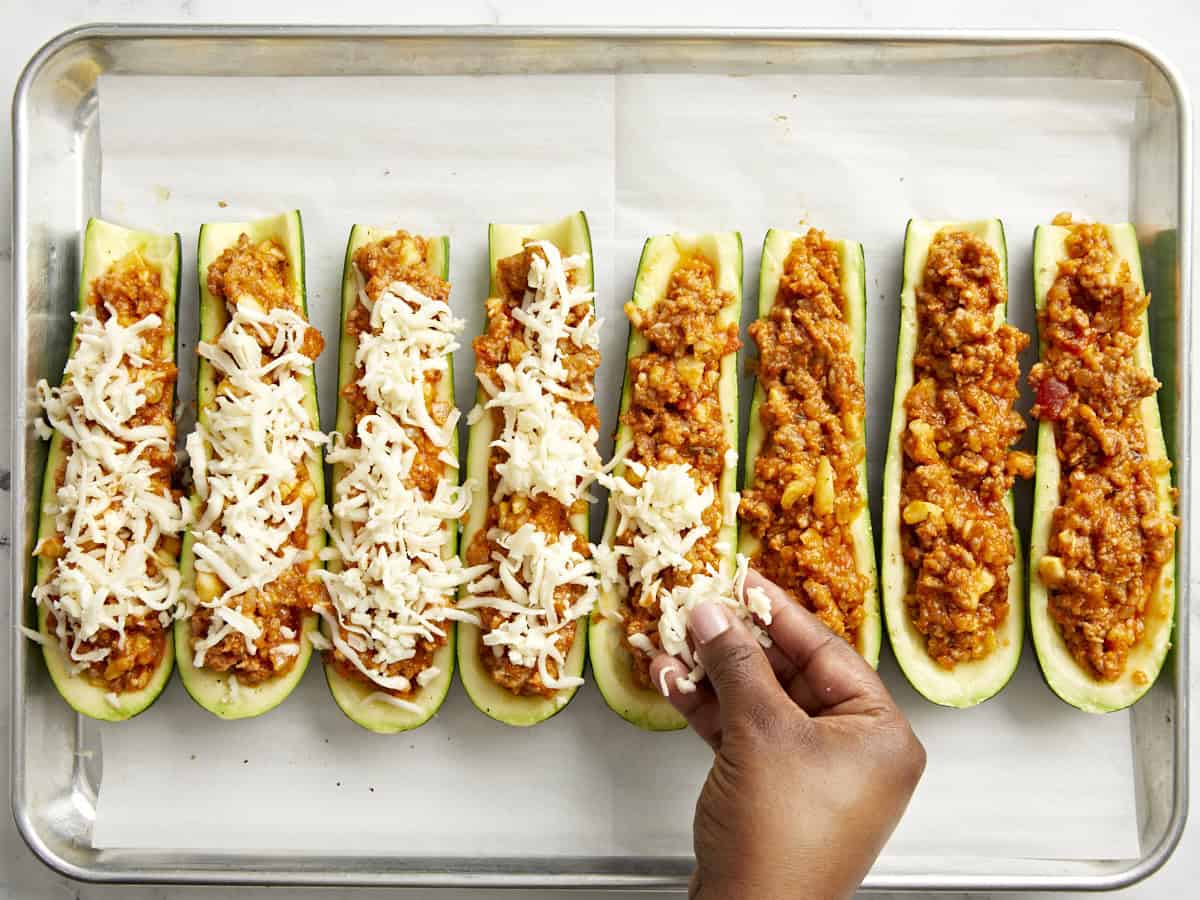 Cheese being added on top of the Zucchini Boats.