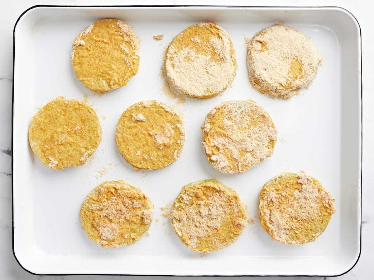 breaded green tomatoes on a baking sheet.