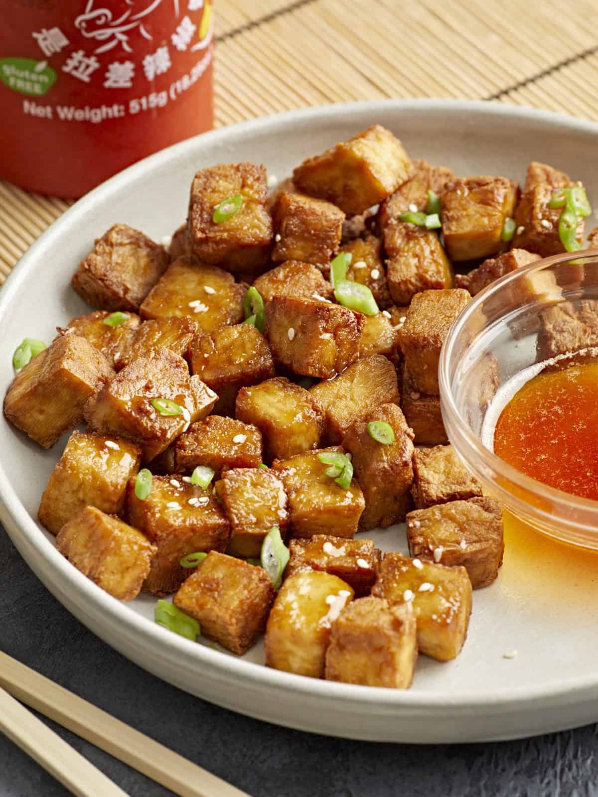 air fryer tofu on a white plate with a bowl of sweet chili dipping sauce.