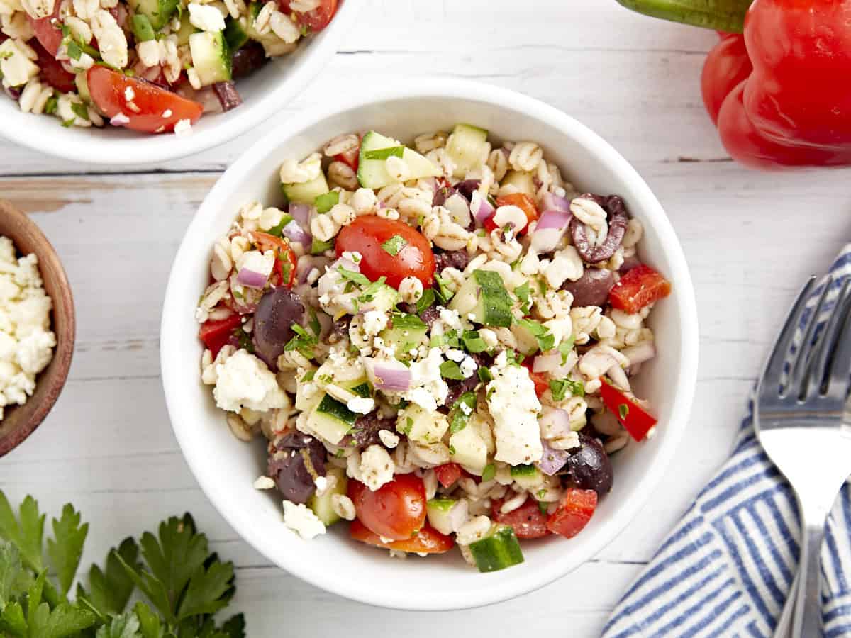 overhead view of a serving of barley salad in a white bowl topped with feta.