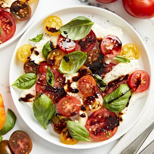 overhead view of a serving of caprese salad on a white plate with balsamic glaze.