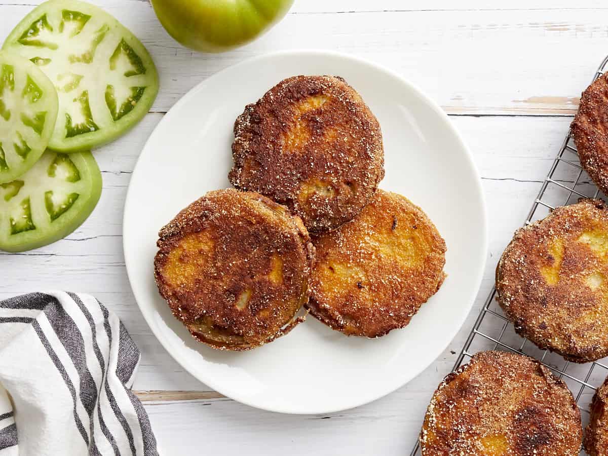 overhead view of 3 fried green tomatoes on a white plate.