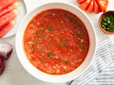 overhead view of watermelon gazpacho in a white bowl with minced fresh herbs.